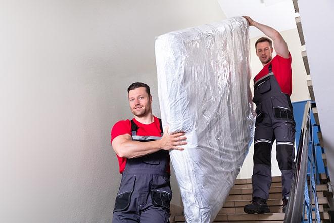 two workers safely transporting a box spring out of a house in Cardiff By The Sea